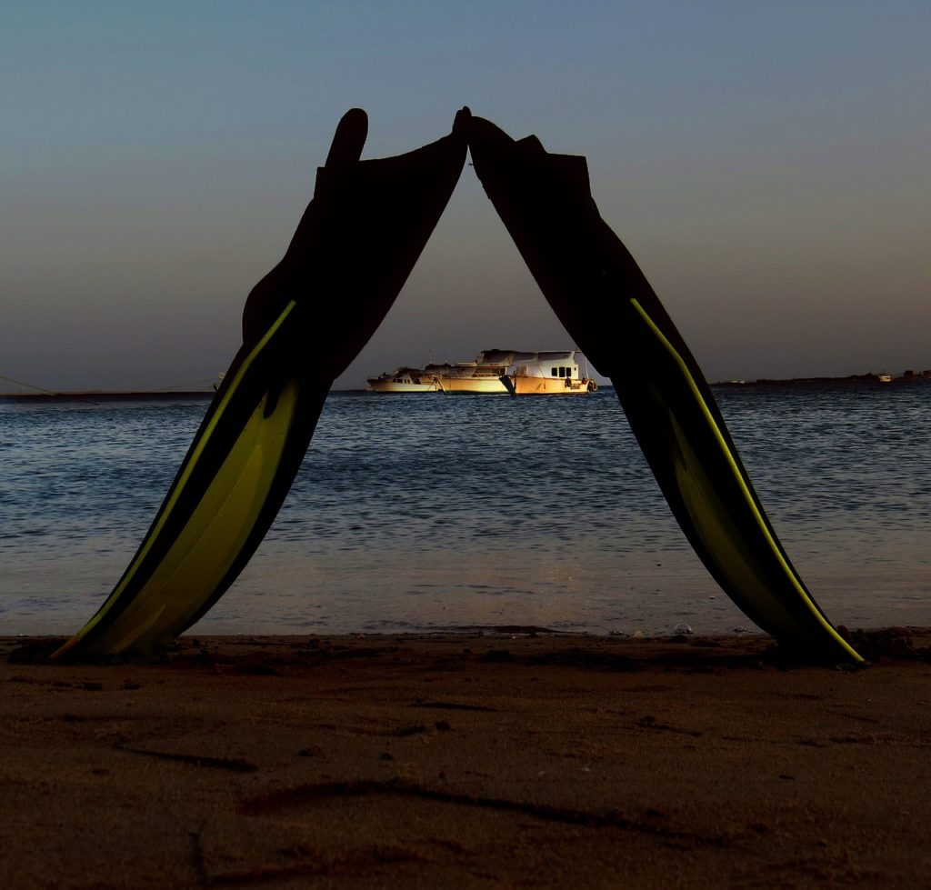 How can you make sure that you don't get leg cramps? Showing a pair of fins on the beach to represent the issue.