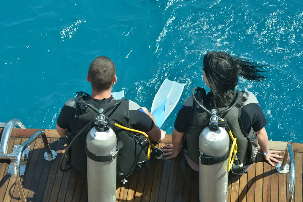 Scuba divers seated for entry into the water