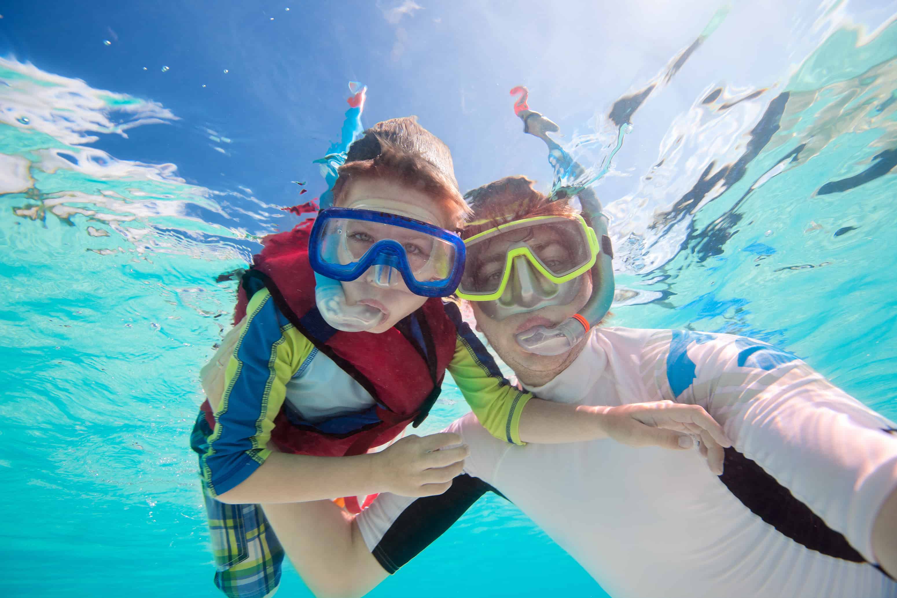 Father snorkeling with son - children have fun snorkeling