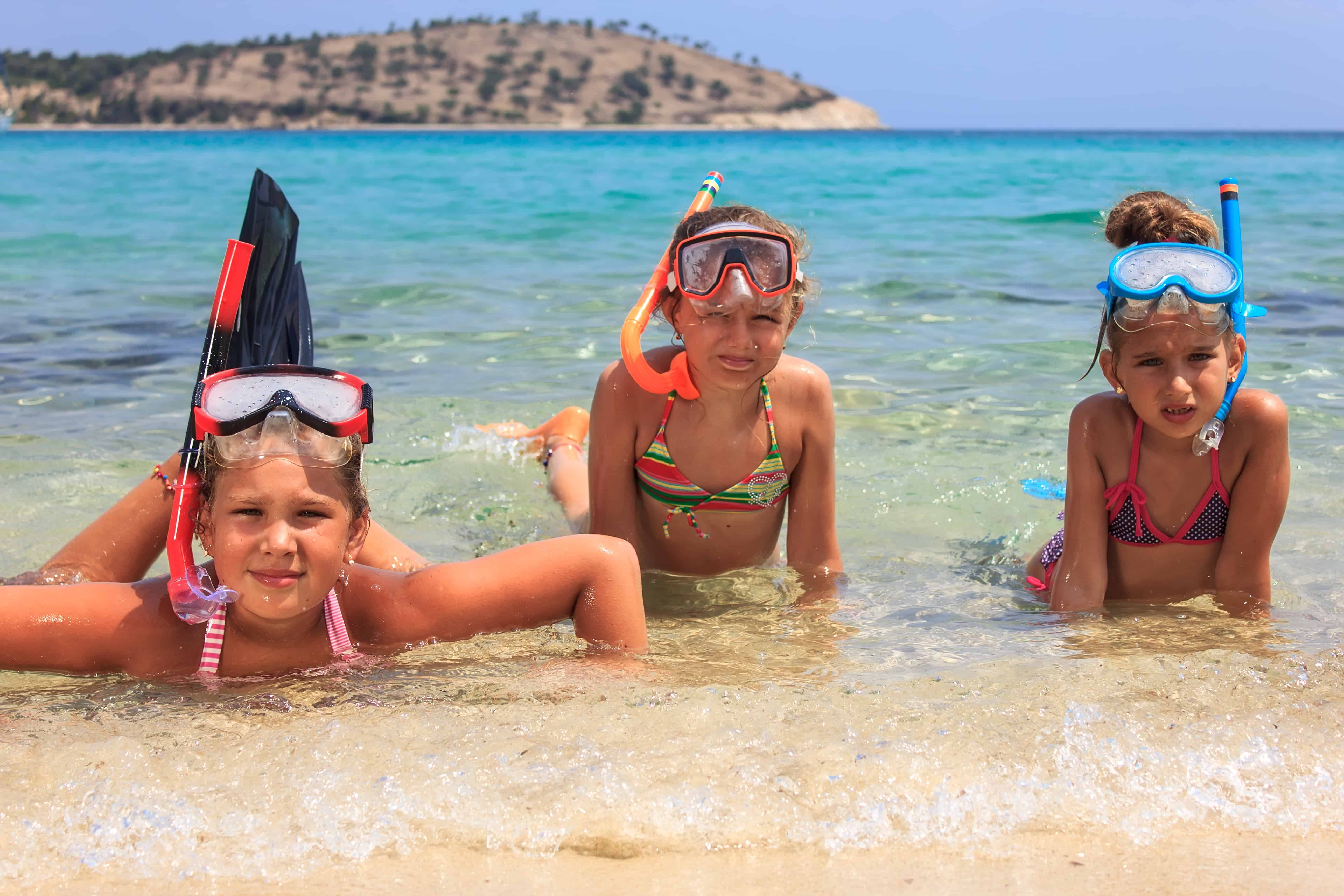 Three girls snorkeling in the ocean - Find out what you need to know to go snorkeling with your kids